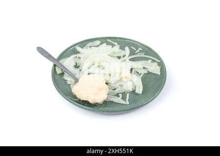 Oignon tranché avec mayonnaise et une cuillère à thé en argent sur une plaque en céramique, isolé sur blanc Banque D'Images