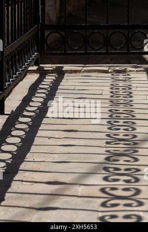 Les ombres d'une balustrade ornée projettent sur un sol en pierre, créant des formes intéressantes et une image presque monochrome. Banque D'Images