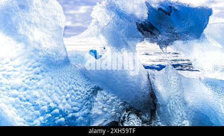 Grande formation de glace sur la côte. A travers ses irrégularités, vous pouvez voir l'océan. La glace brille dans différentes nuances de bleu. Banque D'Images