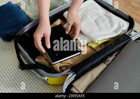 Une jeune femme place soigneusement un livre à l'intérieur d'une valise, se préparant à des vacances remplies d'aventure. Banque D'Images