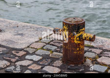 Vieux poteau d'amarrage en acier rouillé sur une jetée et une mer sur le fond, sur la ville, bannière avec copyspace Banque D'Images