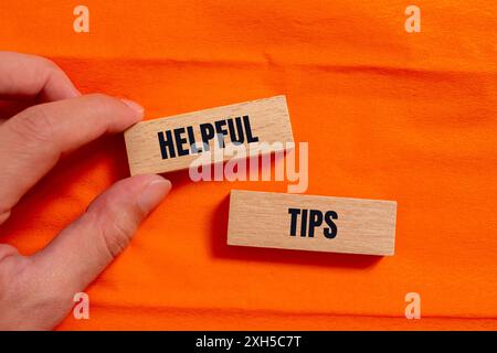 Conseils utiles message écrit sur des blocs de bois avec fond orange. Symbole astuces conceptuelles utiles. Copier l'espace. Banque D'Images