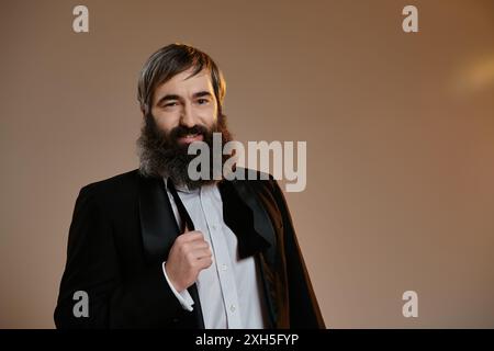 Un homme dans un smoking ajuste son noeud papillon, l'air confiant et dapper. Banque D'Images