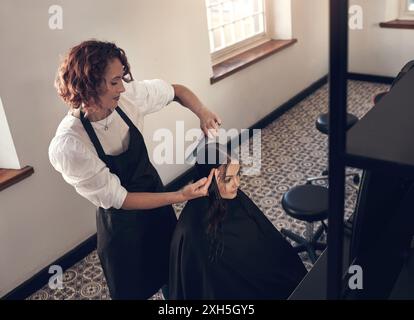 Ciseaux, coupe et coiffeur avec client dans le salon pour les pointes fourchues avec traitement d'hydratation. Beauté, service et taille esthéticienne pour la coiffure Banque D'Images