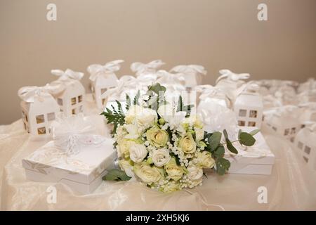 Roses blanches et bouquet de souffle de bébé couché sur la table près des faveurs de mariage Banque D'Images