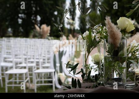 Décorations florales élégantes de cérémonie de mariage en plein air avec roses blanches, branches d'olivier et herbe de pampa Banque D'Images