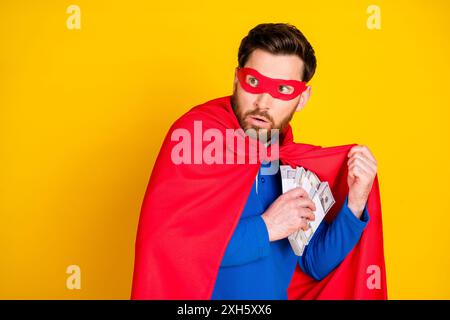 Portrait photo de beau jeune gars cachant voleur d'argent tourner autour effrayé habillé élégant vêtement bleu isolé sur fond de couleur jaune Banque D'Images