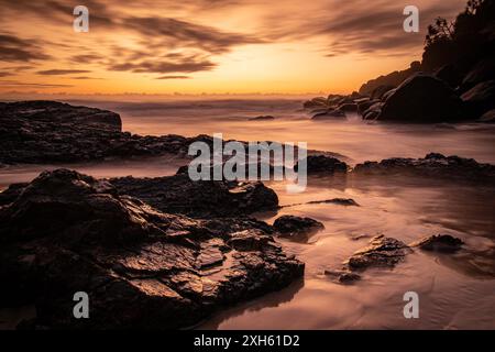 Sunset with shiny silky water around rocks on Gold Coast Stock Photo