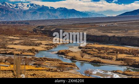 Rivière Indus coulant à travers l'herbe sèche d'hiver avec des montagnes enneigées autour dans le Ladakh Banque D'Images