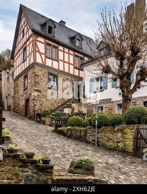 Charmantes maisons à colombages près d'une rivière avec un château médiéval sur une colline brumeuse à Monreal, en Allemagne. Banque D'Images