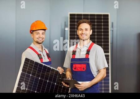 Portrait ouvriers masculins en uniforme tenant le panneau solaire à l'intérieur travaillant sur le chantier de construction Banque D'Images