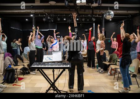 02 juillet 2024, Bavière, Nuremberg : les femmes s'étirent pendant une répétition de chœur pour détendre leur corps pour le chant après. Avec un répertoire moderne qui va au-delà de la littérature chorale habituelle, les Desirenen connaissent un grand succès à Nuremberg et attirent de plus en plus de chanteuses. Deux autres chœurs de femmes ont déjà émergé de celles qui s'intéressent au projet de chœur fondé en 2013. Photo : Pia Bayer/dpa Banque D'Images