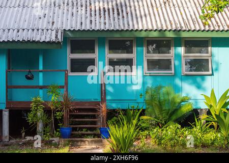 Une maison colorée sur l'île de Cocos caractérisée par des murs en panneaux de bois peints de couleurs vives et un toit en tôle ondulée rouillée. Banque D'Images