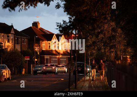 Un ciel sombre et une lumière du soleil dramatique éclatent sur les maisons résidentielles de banlieue de l'époque édouardienne dans le quartier sud de Londres de Lambeth, le 11 juillet 2024, à Londres, en Angleterre. De nombreuses régions du Royaume-Uni ont déjà eu leurs précipitations mensuelles moyennes avec 66cm de pluie sur les sept premiers jours du mois - 139% du total attendu pour tout le mois de juillet. Banque D'Images