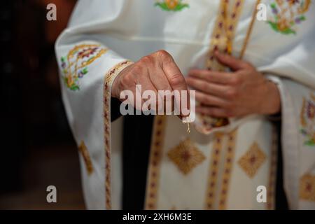 Prêtre tenant un pendentif en croix dorée lors d'un baptême orthodoxe d'un bébé enfant Banque D'Images