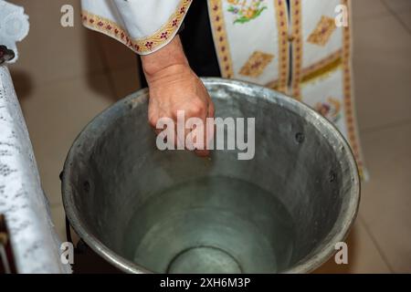 Prêtre tenant un pendentif en croix dorée lors d'un baptême orthodoxe d'un bébé enfant Banque D'Images