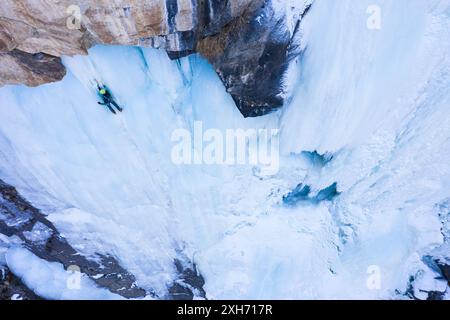 L'homme mène sur la glace. Escalade de glace sur la cascade gelée, vue aérienne. Vallée de Barskoon, Kirghizistan Banque D'Images