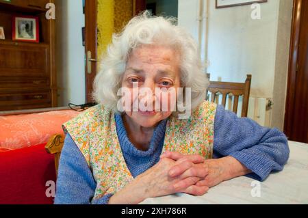 Portrait d'une femme âgée à la maison, souriant et regardant la caméra. Banque D'Images