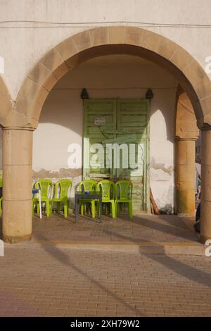 Un café avec volets au Maroc avec une arche extérieure et des tables et des chaises de couleur citron vert. Banque D'Images