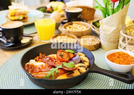 English petit déjeuner dans une poêle avec œufs frits, saucisses, bacon, champignons, haricots et tomates Banque D'Images