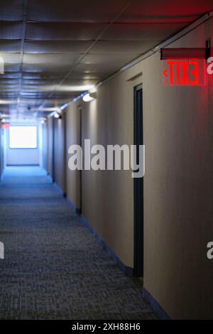 Panneaux lumineux rouges lumineux pour sortie de secours dans le couloir avec des flèches pointant vers la sortie du bâtiment Banque D'Images