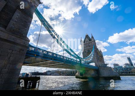 Vue panoramique sur la Tamise avec le ciel bleu et le soleil avec ses rayons sortant de derrière les nuages rétroéclairant le Tower Bridge de Londres Banque D'Images