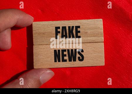Faux mots de nouvelles écrits sur des blocs de bois avec fond rouge. Symbole conceptuel de fausses nouvelles. Copier l'espace. Banque D'Images