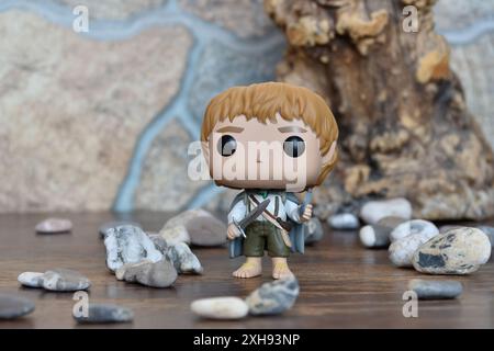 Funko Pop figurine d'action vinyle de Sam hobbit du film fantastique le Seigneur des anneaux. Jouet de collection tenant l'épée debout près du vieil arbre et des pierres. Banque D'Images