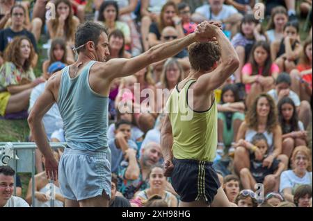 Viladecasn, ESPAGNE - 12 JUILLET 2024 : au milieu d'une foule de spectateurs, deux athlètes se tiennent la main, créant une image touchante de la solidarité sportive. Banque D'Images