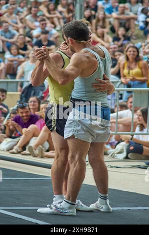 Viladecasn, ESPAGNE - 12 JUILLET 2024 : cette image capture deux athlètes au milieu d'une danse, entourés de spectateurs, soulignant la fusion de l'athl Banque D'Images