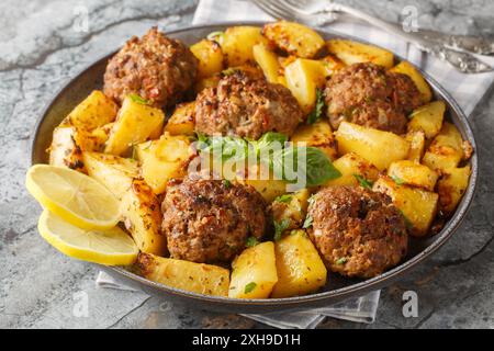 Des boulettes de viande et des quartiers de pommes de terre cuits au four maison en gros plan sur l'assiette sur la table. Horizontal Banque D'Images