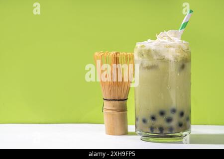 Thé à bulles vert matcha boba avec perle de tapioca. Boisson glacée froide asiatique tendance avec boules de tapioca foncées et crème fouettée non laitière, espace copie Banque D'Images