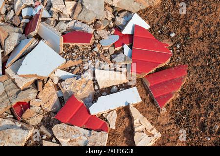 Carreaux de céramique rouge et blanc cassés en petits morceaux tranchants, jetés sur le sol volcanique dans la nature. Lanzarote, Îles Canaries, Espagne. Banque D'Images