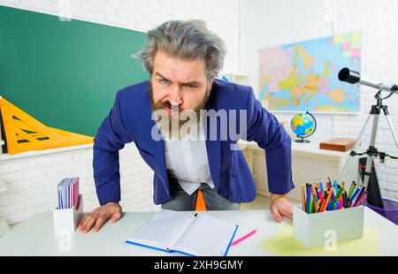 Professeur d'école masculin en colère au bureau à l'université. L'homme barbu en costume travaille en classe. Concept d'apprentissage et d'éducation. Le professeur d'université a l'air angril Banque D'Images