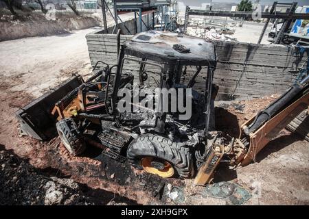 Naplouse, Palestine. 12 juillet 2024. Vue générale d'un bulldozer brûlé par des colons juifs de la colonie israélienne de Homesh. Un groupe de colons masqués a attaqué des magasins et des maisons dans le village de Bazaria, au nord de la ville de Naplouse, en Cisjordanie. Crédit : SOPA images Limited/Alamy Live News Banque D'Images