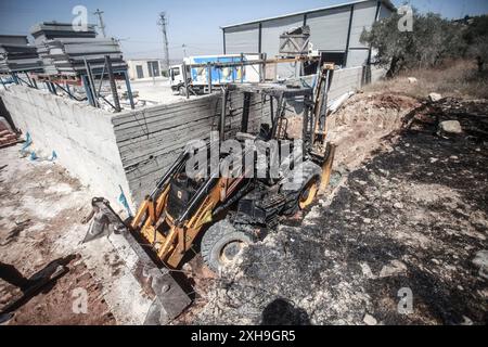 Naplouse, Palestine. 12 juillet 2024. Vue générale d'un bulldozer brûlé par des colons juifs de la colonie israélienne de Homesh. Un groupe de colons masqués a attaqué des magasins et des maisons dans le village de Bazaria, au nord de la ville de Naplouse, en Cisjordanie. Crédit : SOPA images Limited/Alamy Live News Banque D'Images