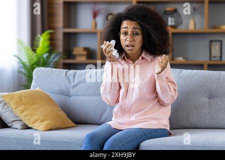 Femme sur le canapé tenant le tissu éprouvant des symptômes d'allergie dans un environnement confortable à la maison montrant l'inconfort Banque D'Images