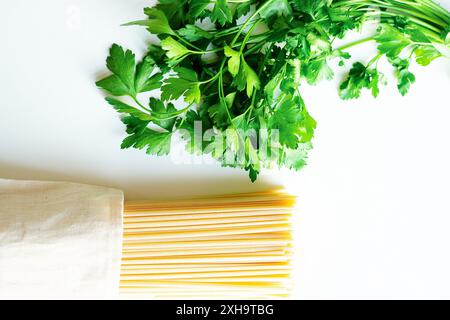 Persil italien et spaghetti sur fond blanc Banque D'Images