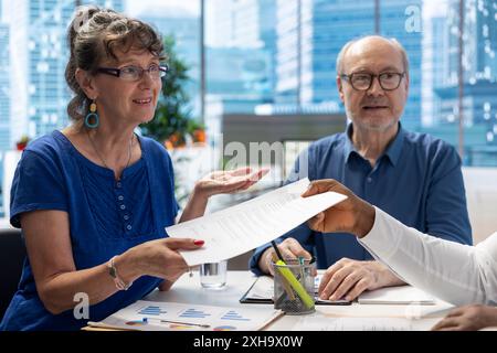 Conseiller financier remettant les documents du régime de retraite aux personnes âgées, obtenant un contrat avec une police d'assurance vie. Courtier conseiller les clients pour choisir une option de retraite appropriée. Banque D'Images