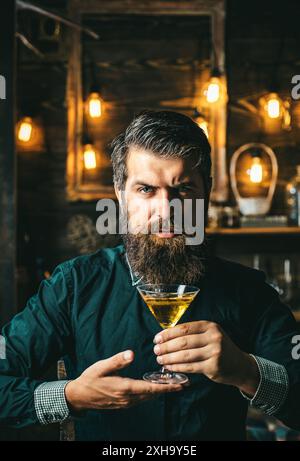 Bel homme pensif tient un verre de whisky. Soirée buvez Banque D'Images