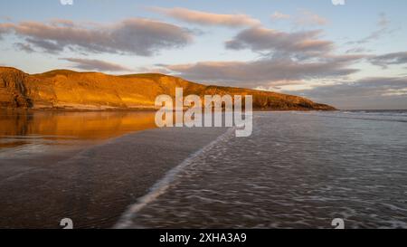 Coucher de soleil sur les falaises à Dunraven Bay, pays de Galles du Sud, avec reflets et tons chauds Banque D'Images