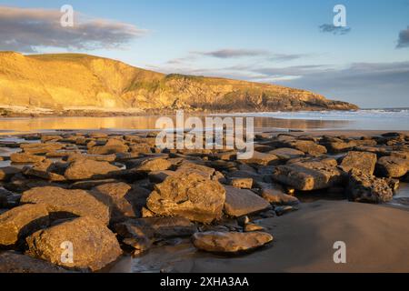 Coucher de soleil sur les falaises à Dunraven Bay, pays de Galles du Sud, avec reflets et tons chauds Banque D'Images