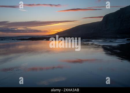 Coucher de soleil sur les falaises à Dunraven Bay, pays de Galles du Sud, avec reflets et tons chauds Banque D'Images