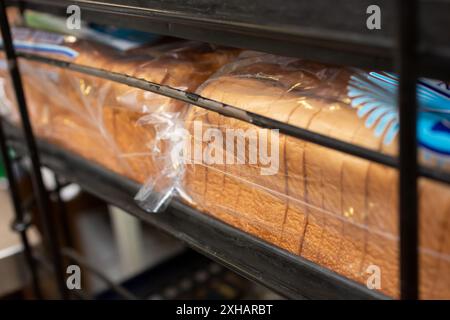 Une vue de plusieurs sacs de pain blanc tranché, sur une grille à plateau, dans un cadre de cuisine de restaurant. Banque D'Images