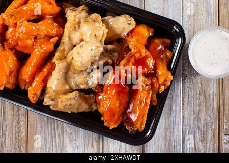 Vue de dessus d'un contenant à emporter de saveurs variées d'ailes de poulet. Banque D'Images