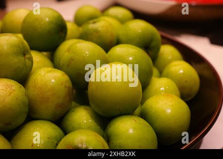 Prunes vertes dans un bol sur une table Banque D'Images