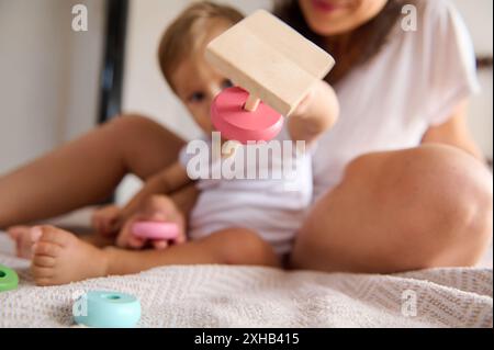 Gros plan d'une mère et d'un enfant s'engageant dans le temps de jeu avec un jouet en bois. L'accent est mis sur l'interaction et le jouet, mettant en évidence le lien familial et EA Banque D'Images