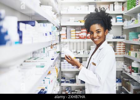 Femme noire, pharmacien et portrait avec produit en clinique pour le stock de médicaments, la lecture et vérifier les informations sur l'étiquette. Sourire, personne féminine et pilules Banque D'Images