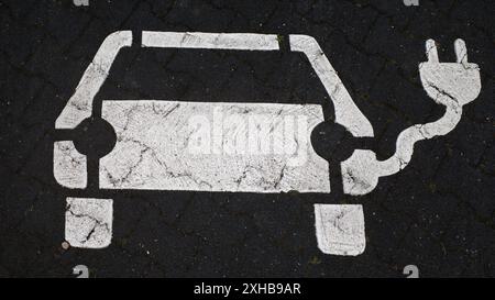 Icône sur l'asphalte pour un parking avec point de recharge pour voitures électriques Banque D'Images