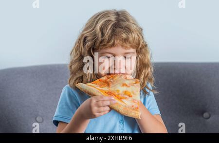 Enfants délicieuses pizzas italiennes. Petit garçon mangeant de la pizza. Mignon petit garçon mange des pizzas. Joyeux jeune garçon adolescent tenant une pizza en tranches Banque D'Images